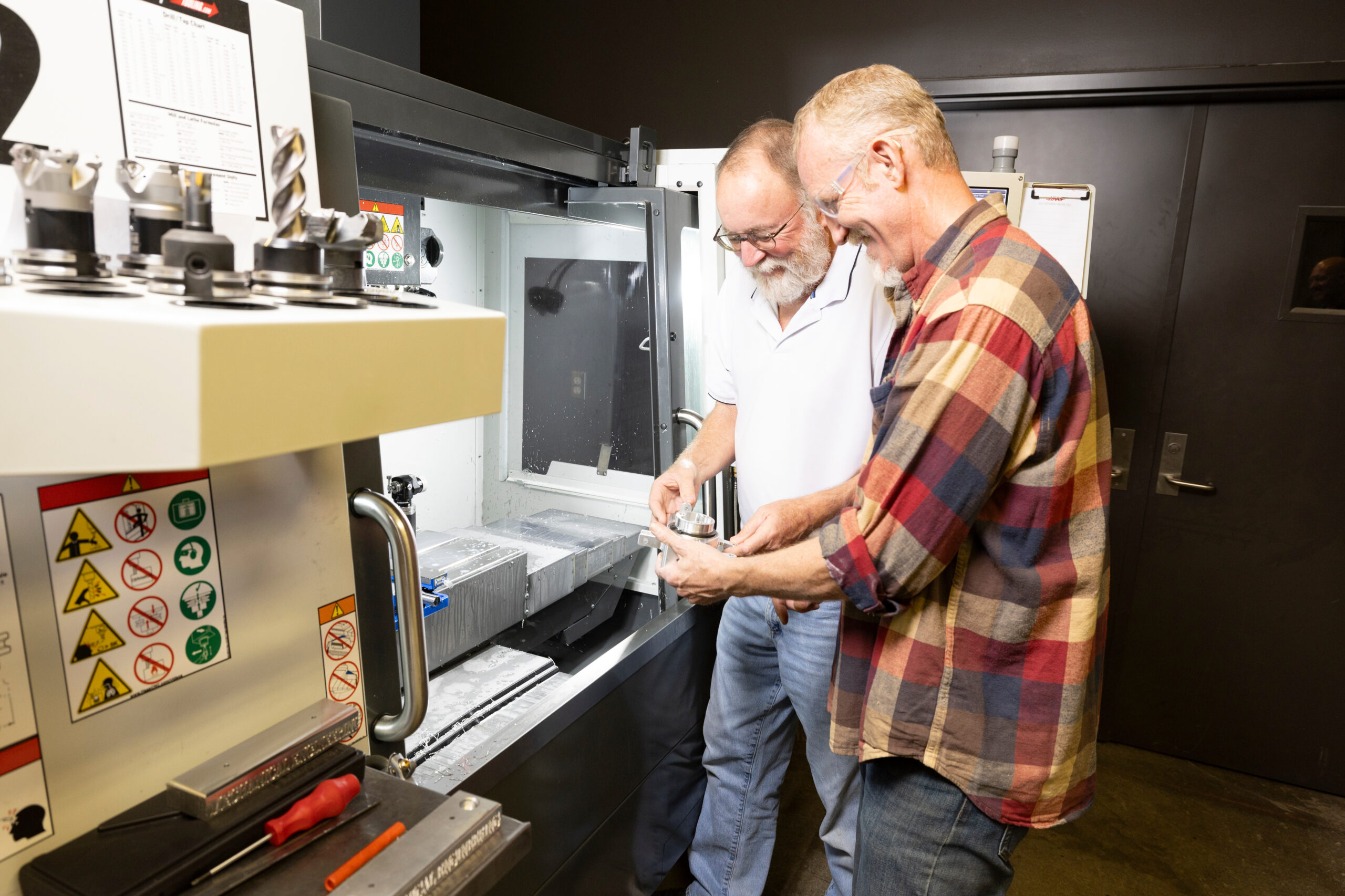 Male Supervisor showing male employee how to operate machinery in a manufacturing setting.