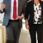 Businessman and woman walking down a ramp wearing business suits.