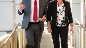 Businessman and woman walking down a ramp wearing business suits.