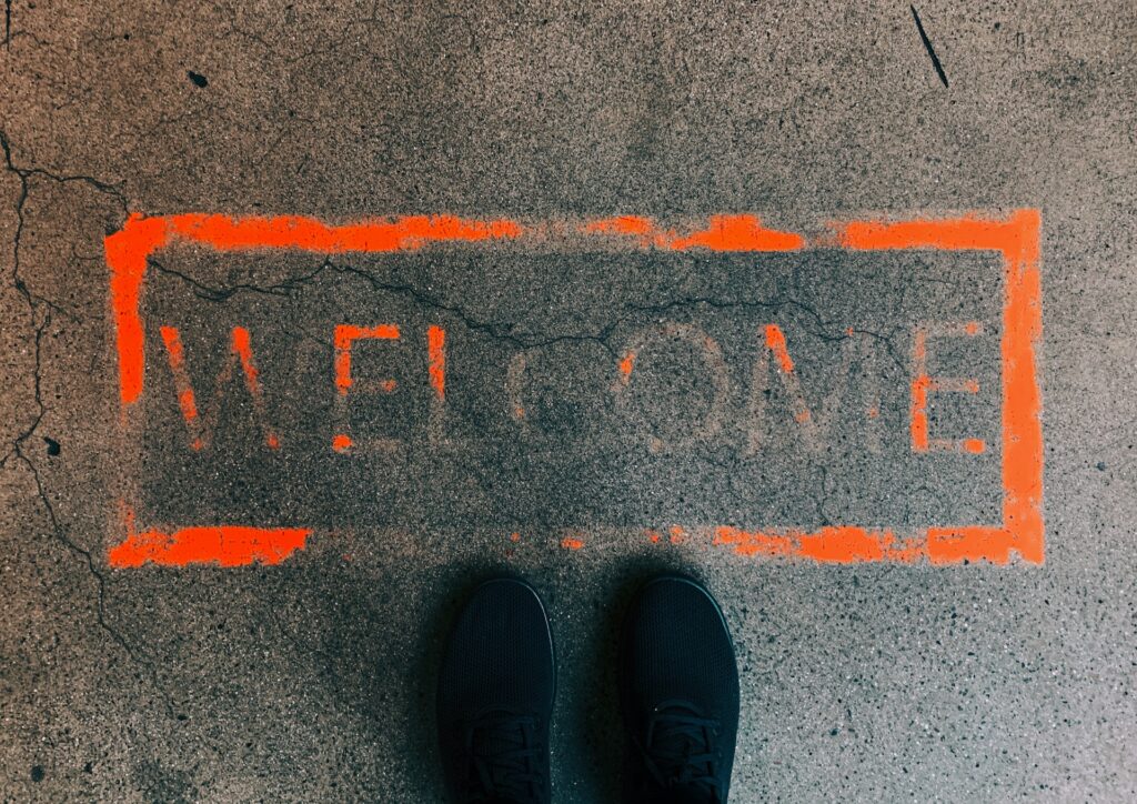 Feet stand on Welcome sign painted on concrete.