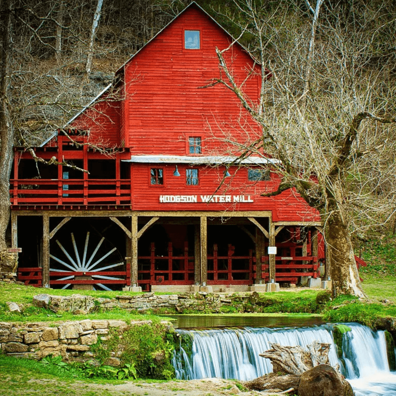 Red barn with small waterfall and stream running in front.