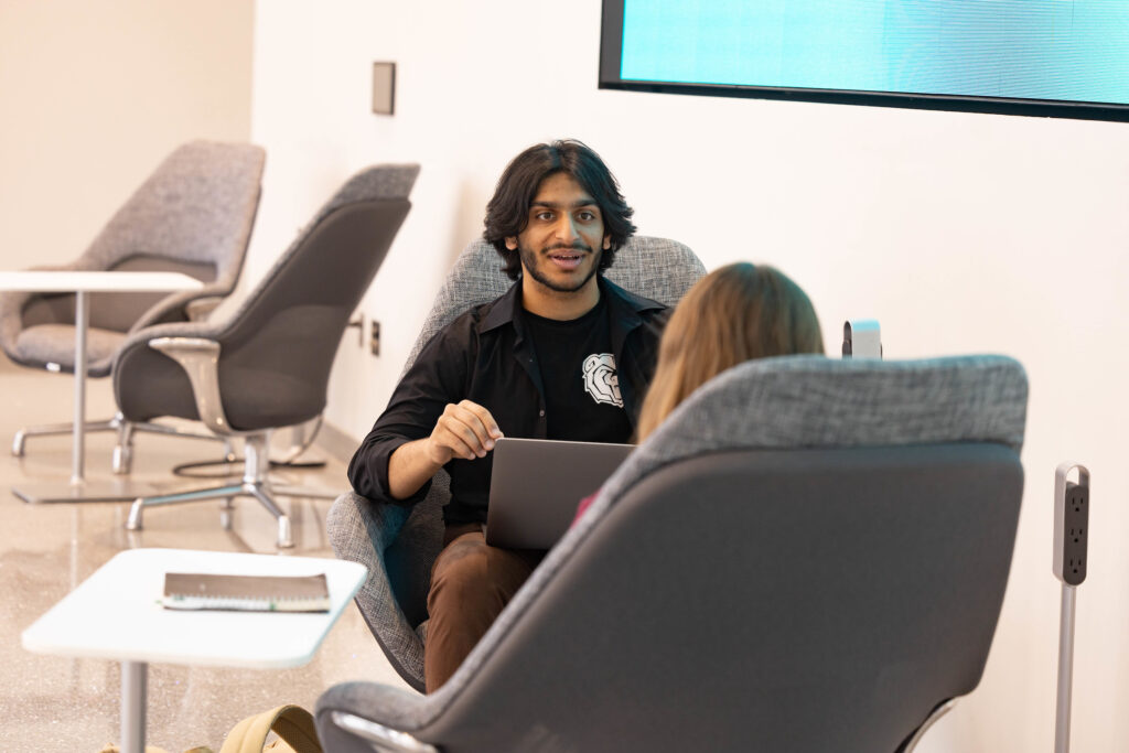 Two students talk in Glass Hall atrium.