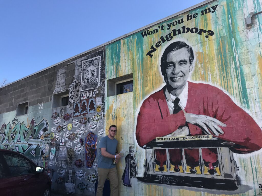 Jeff Rawson stands in front of mural with Mr. Rogers on it.