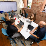 Group of male and female coworkers seated around a conference room table.