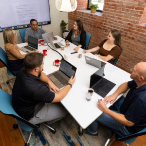 Group of male and female coworkers seated around a conference room table.