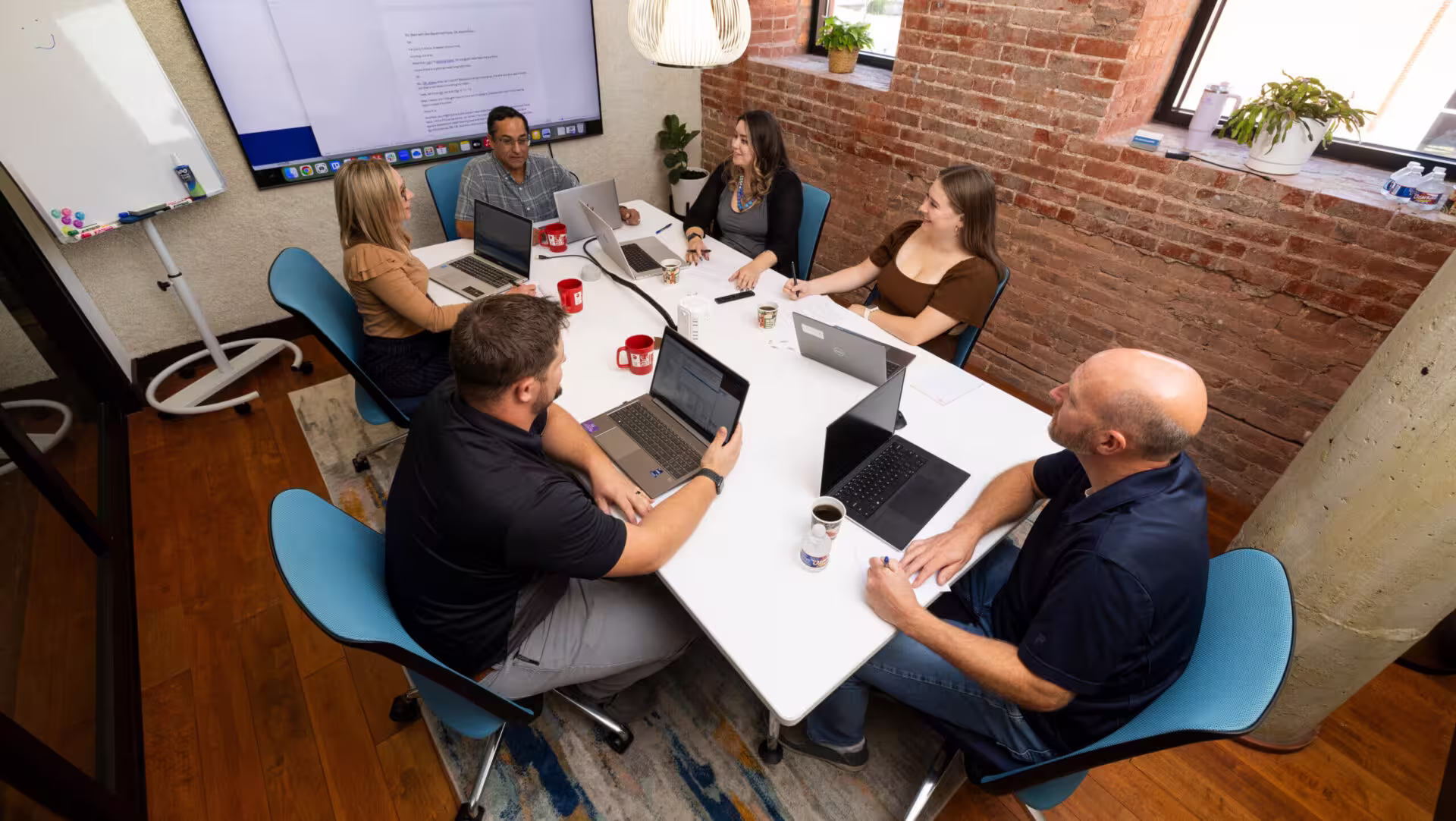 Group of male and female coworkers seated around a conference room table.