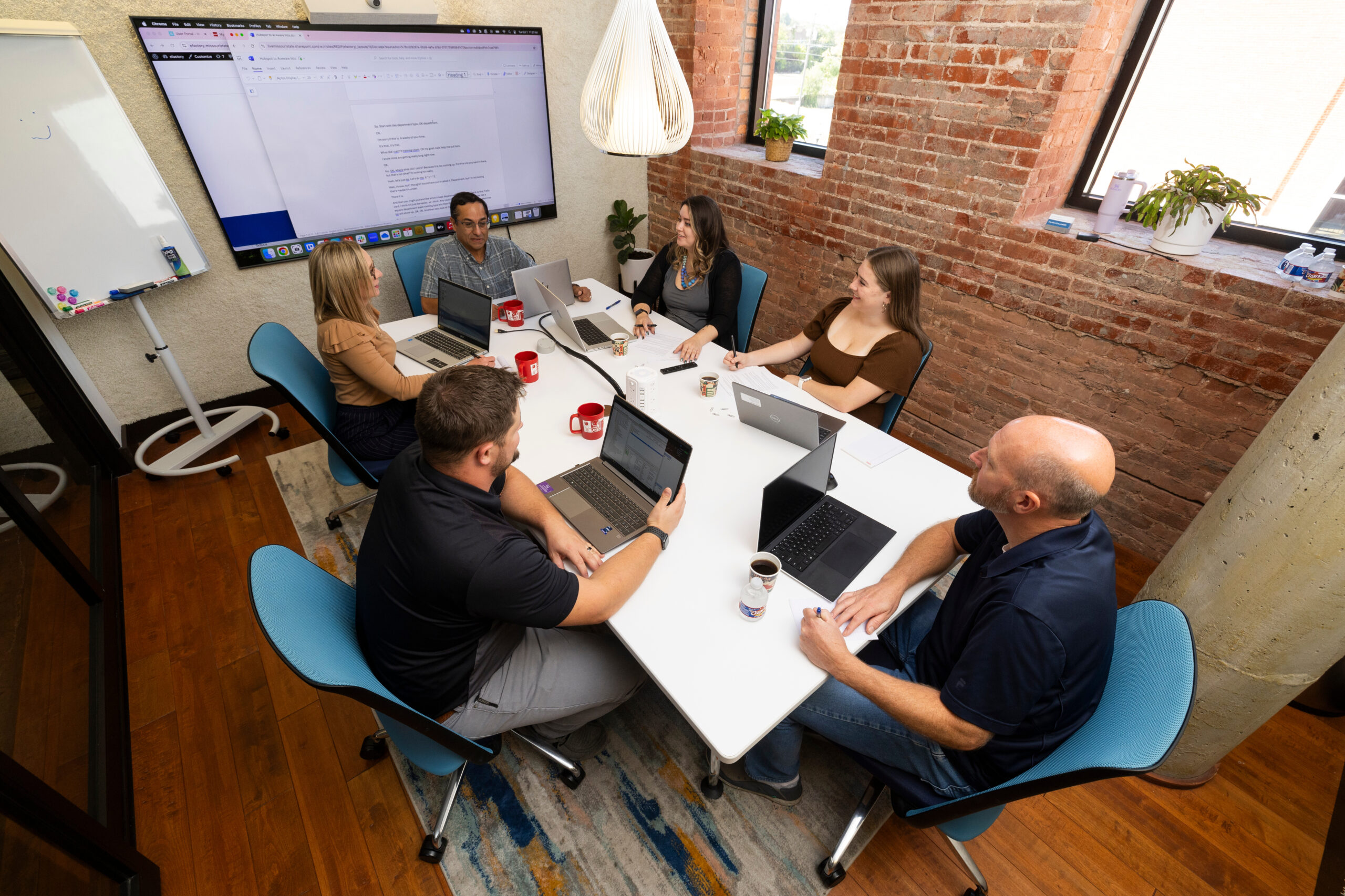 Group of male and female coworkers seated around a conference room table.