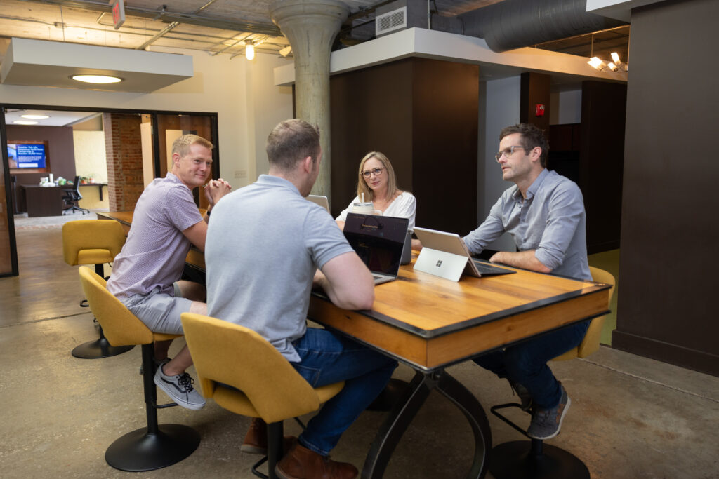 Four people host meeting at conference space.