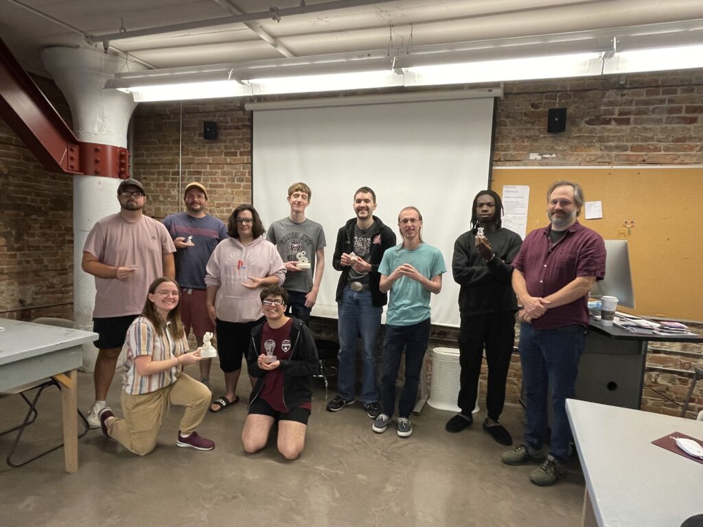 Group of students pose, holding the awards they've created.