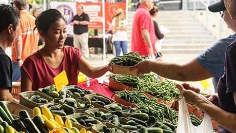 Woman purchases produce at Farmers Market.
