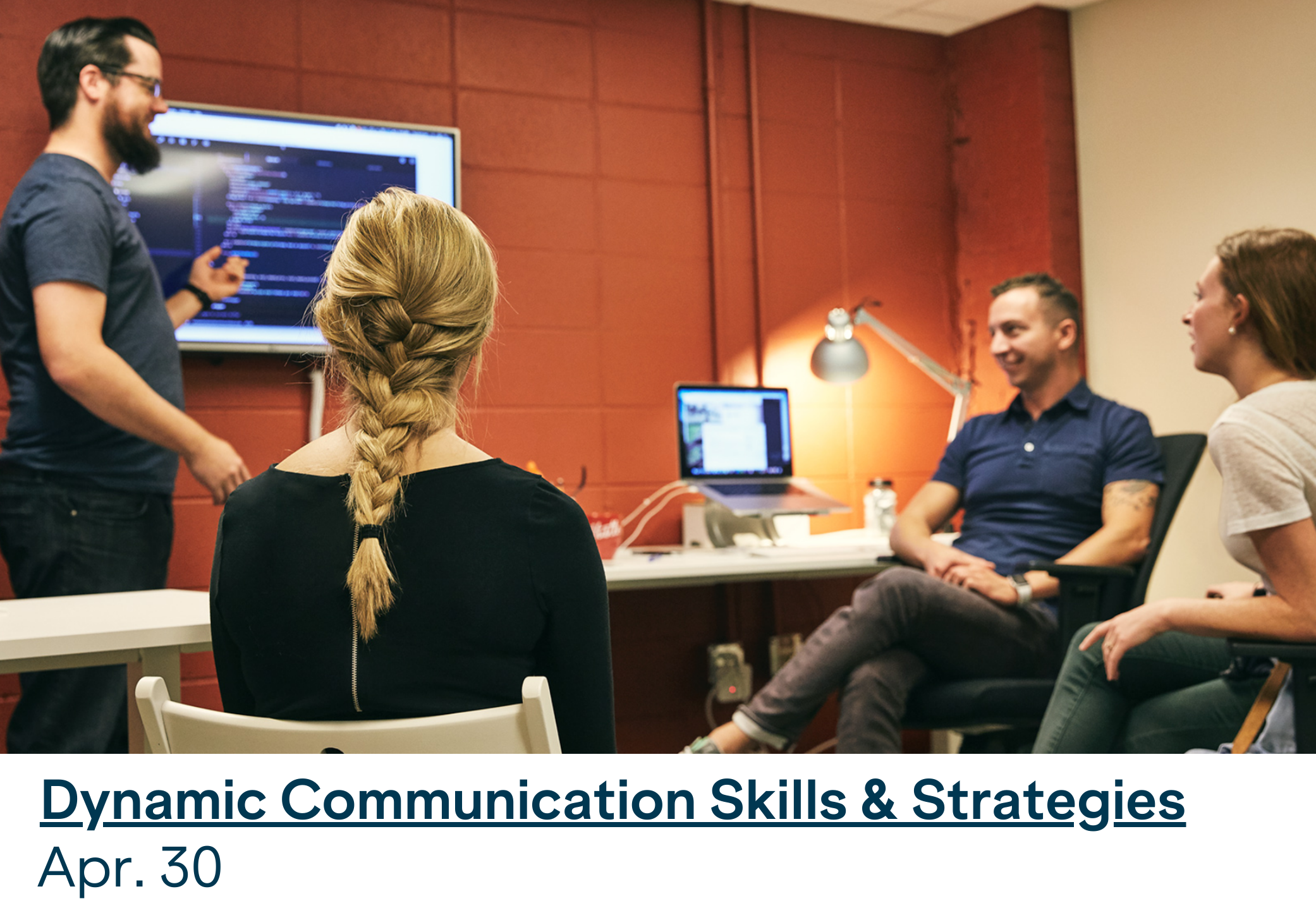 A team of four employees communicate at a meeting.