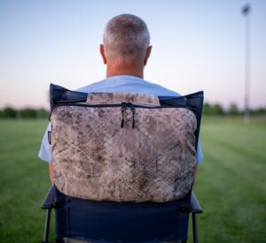 Man watches field with Ponchairo stored on back of chair.