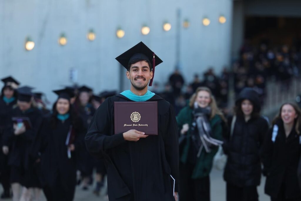 Lucca Barrato stands proudly holding MSU diploma
