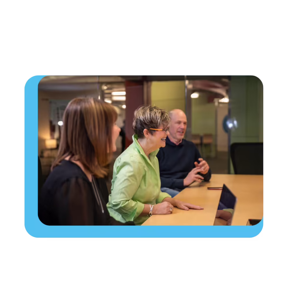 Three people sit at conference table