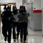 officer moving down hallway in tactical gear with guns drawn