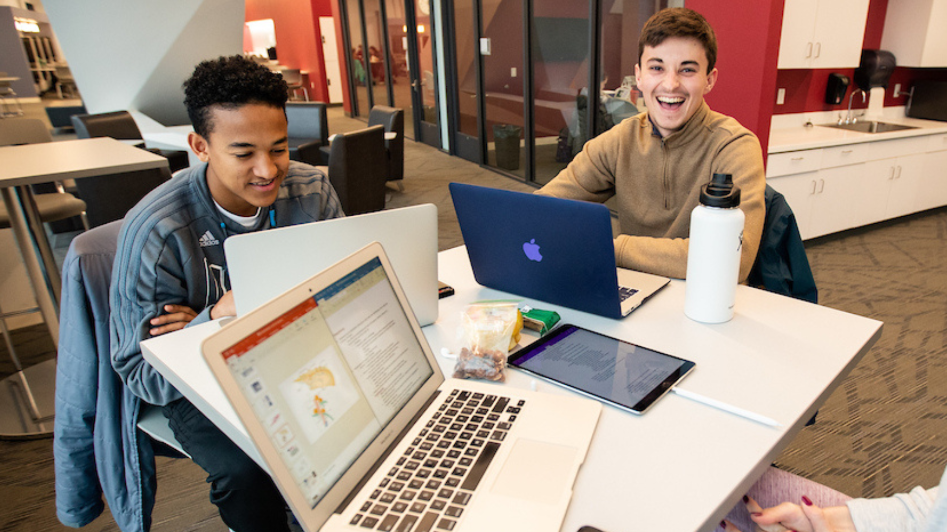 Three students do work on laptops