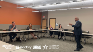 Instructor Larry Stock making a presentation to 3 women and a man in a training room. Sponsor logos for MSU, efactory, Missouri SBDC and Leadership Springfield are shown.