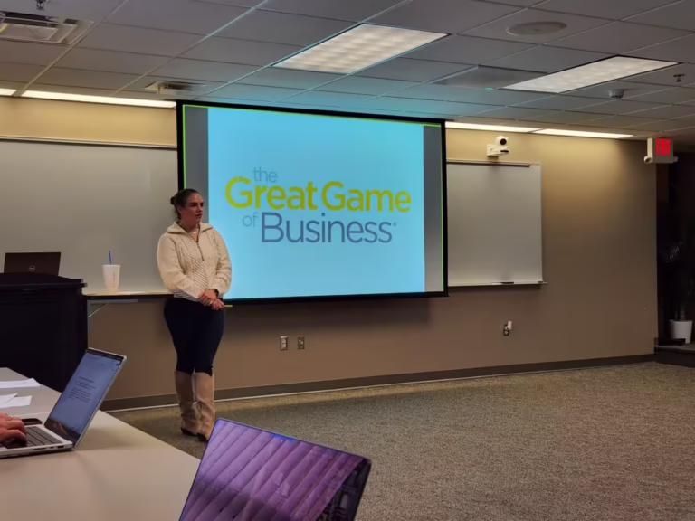 Woman stands in front of projector with Great Game of Business on screen