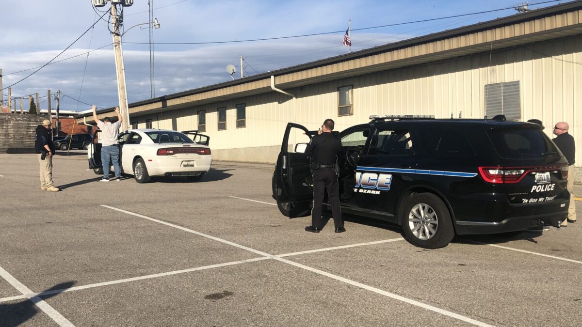 law enforcement stopping car and man standing with hands up under arrest