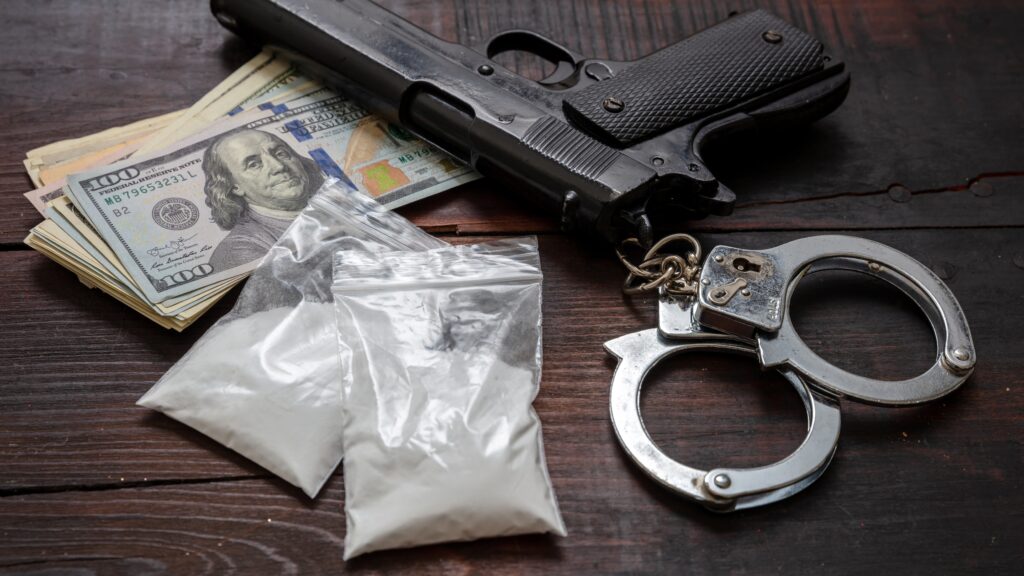 table with gun, money, handcuffs and drugs