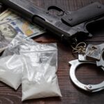 table with gun, money, handcuffs and drugs