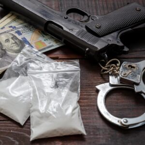 table with gun, money, handcuffs and drugs