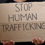 fingers holding sign saying stop human trafficking