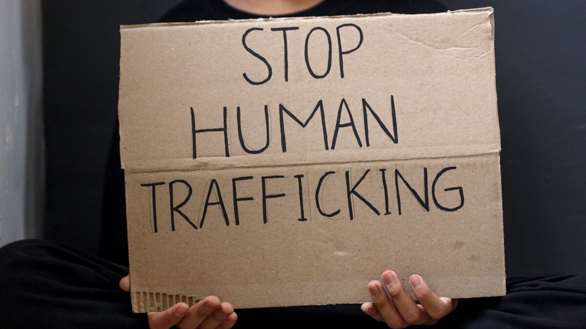 fingers holding sign saying stop human trafficking