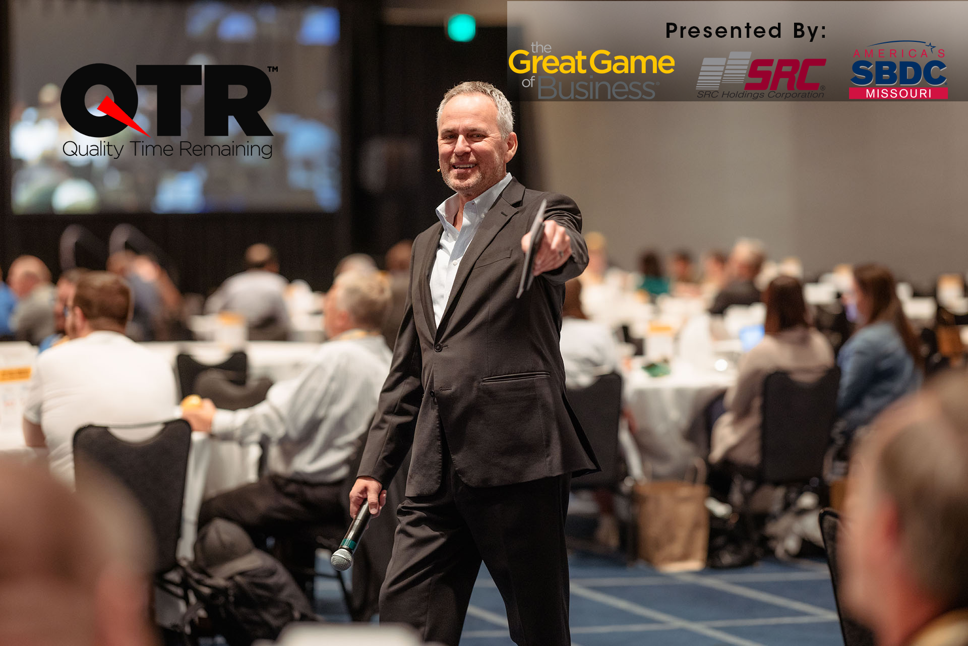 Steve Baker, well known author and speaker presenting to a room full of people. The Great Game of Business, SRC Holdings and Missouri SBDC and Quality Time Remaining (QTR) logos are included.