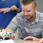 Man sitting behind a LEGO scene with an airplane and LEGO mini-figure.