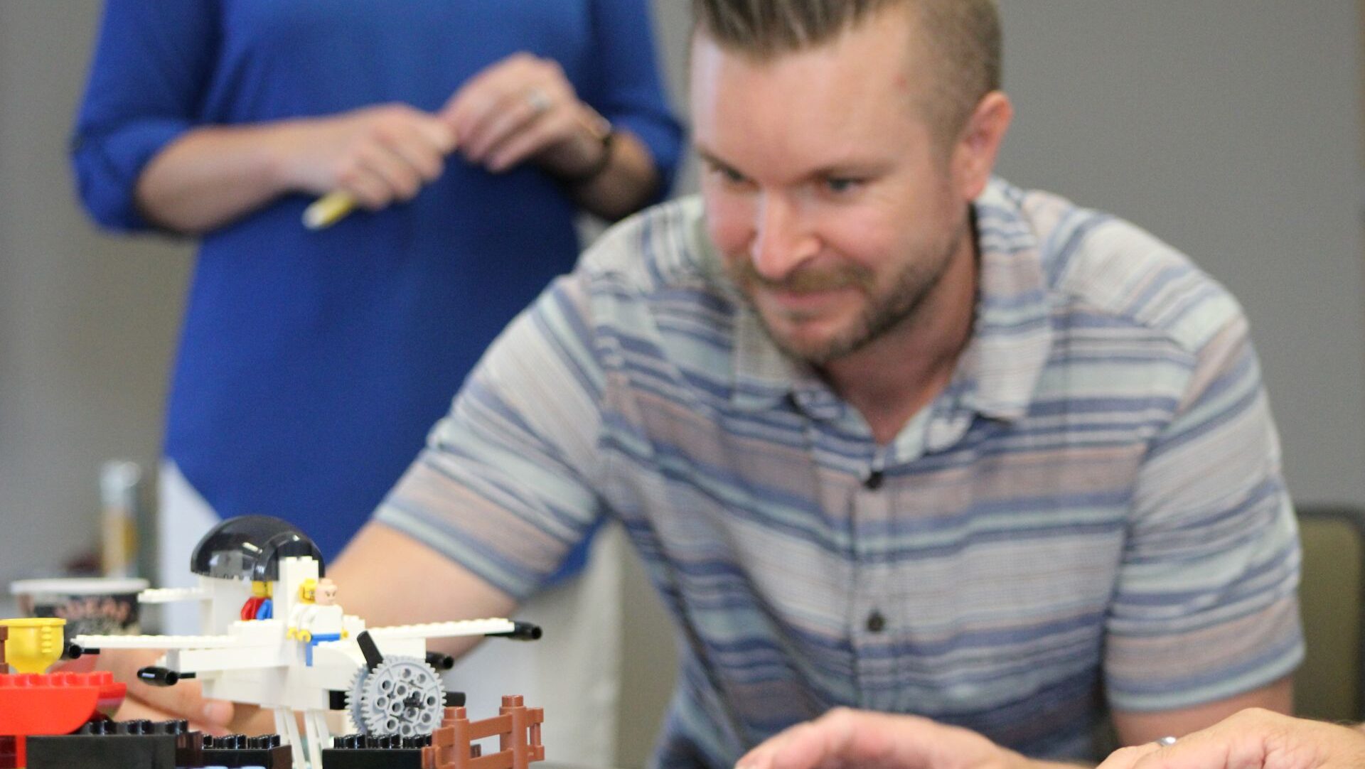 Man sitting behind a LEGO scene with an airplane and LEGO mini-figure.