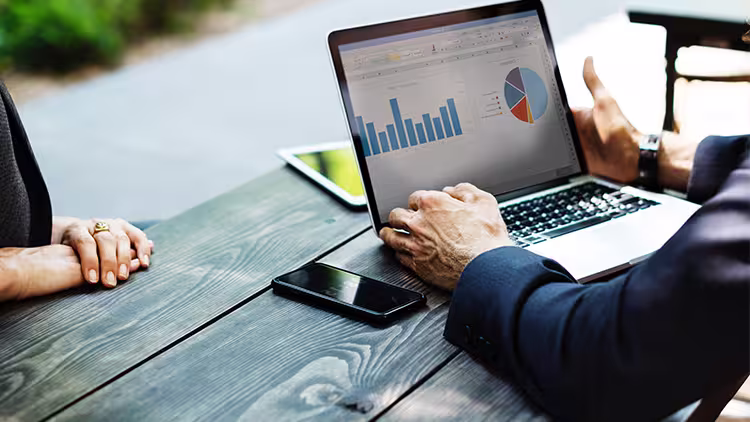 Two people look at accounting software on laptop.