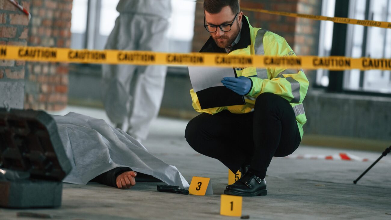 POLICE AT A CRIME SCENE WITH A BODY COVERED BY A SHEET AND POLICE TAPE