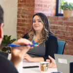 Woman listens as man speaks at conference table