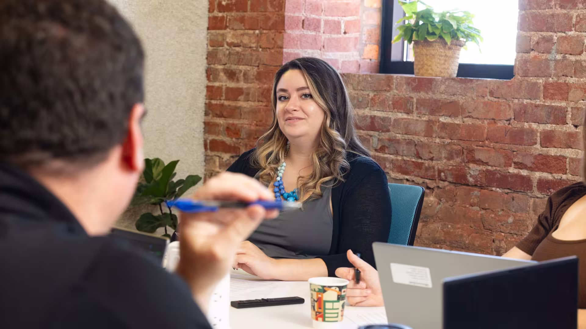 Woman listens as man speaks at conference table