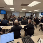 Classroom with students facing towards screens with instructor standing in front