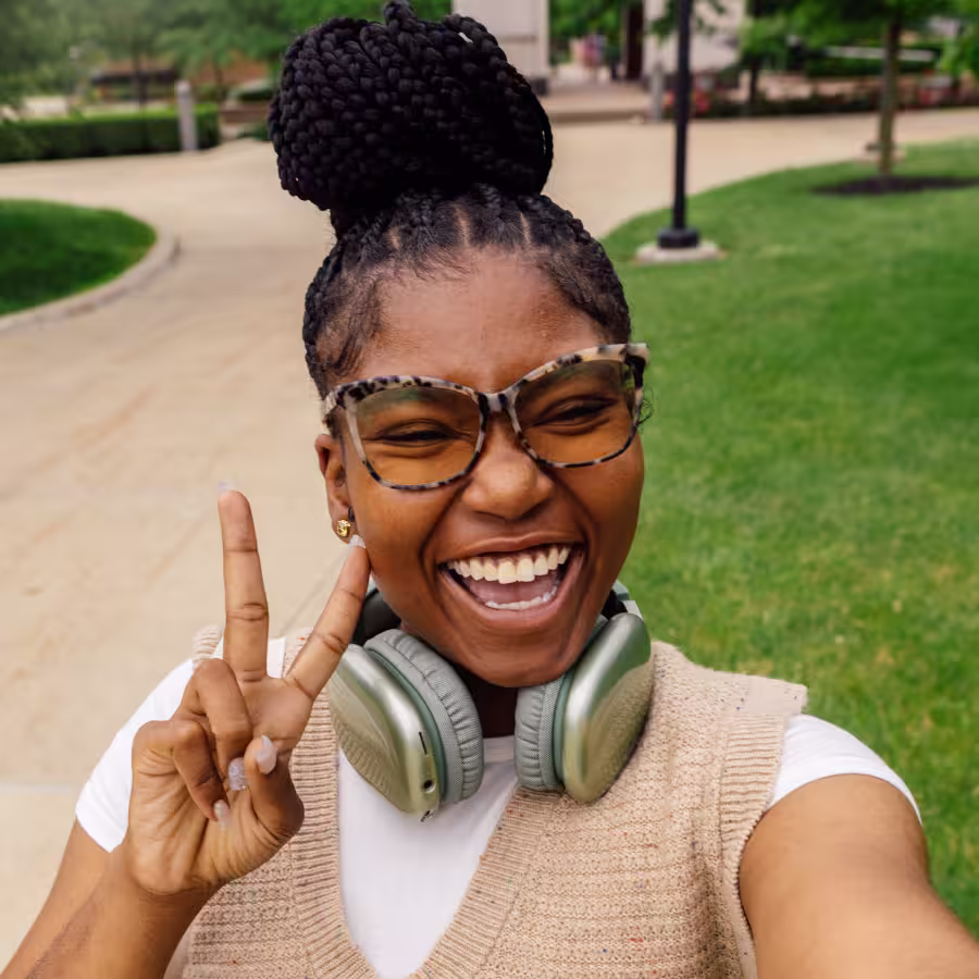 Smiling Black woman flashes a peace sign in a selfie